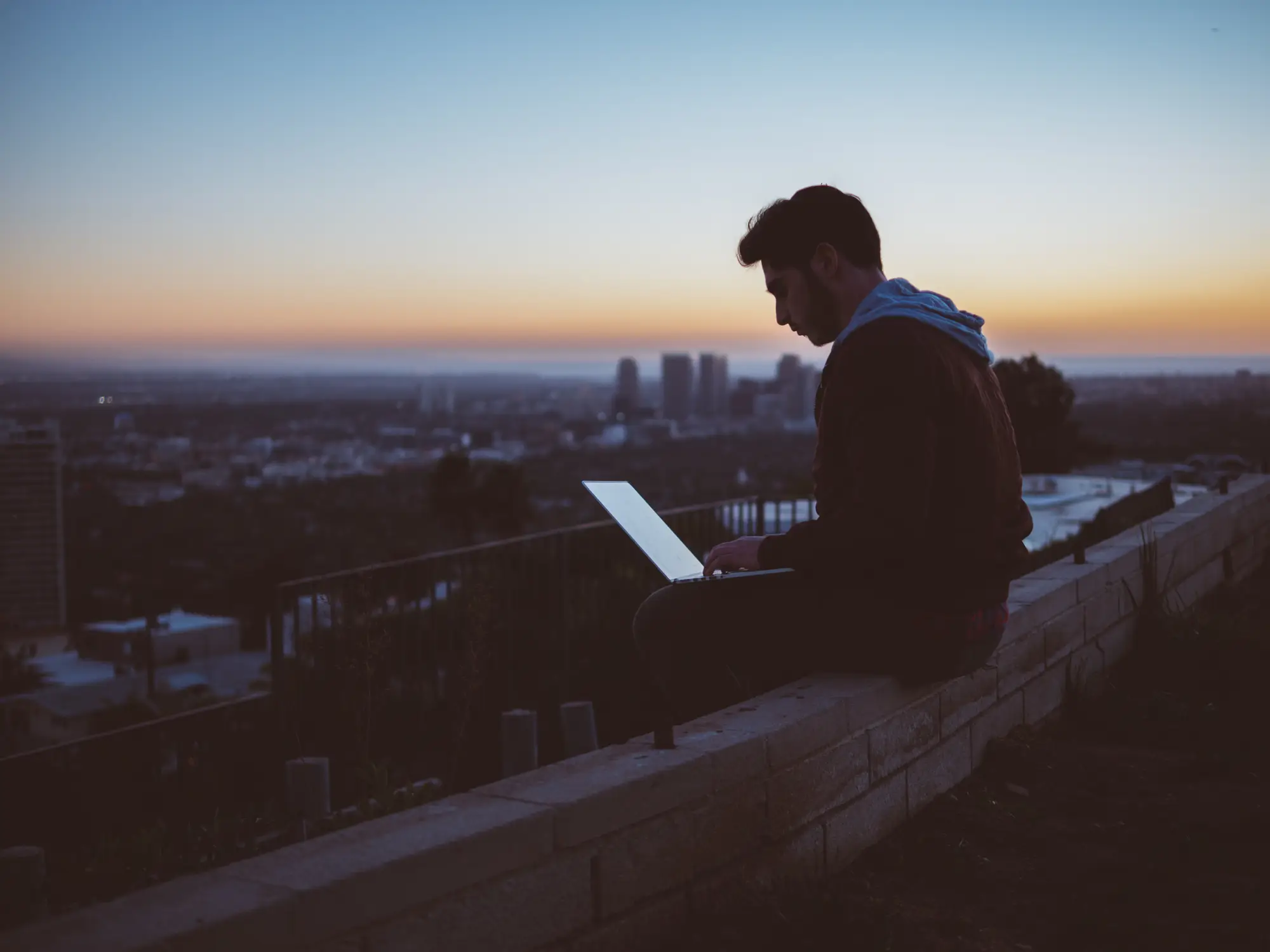 Pessoa com notebook observando a cidade ao entardecer